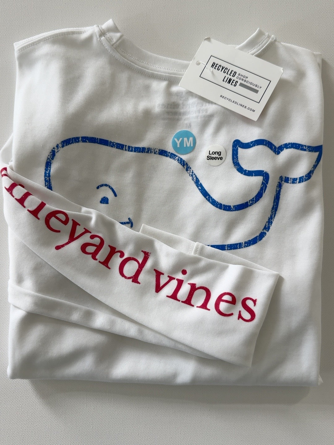 Original photo of white Vineyard Vines long sleeve performance tee with blue whale graphic and red sleeve lettering, boys medium